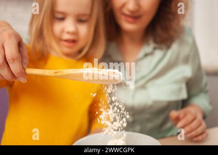 Großmutter und Enkelin machen Kuchen in der Küche, glückliche Familie, Frau und Kind lächeln. Gießen Sie Mehl ein Stockfoto