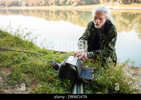 Senior-Konzept. Ein Fischer auf dem Fluss fängt Raubfische. Nützliches Hobby, schöner Herbst, aktiver gesunder Lebensstil. Sammelt einen Beutel Stockfoto