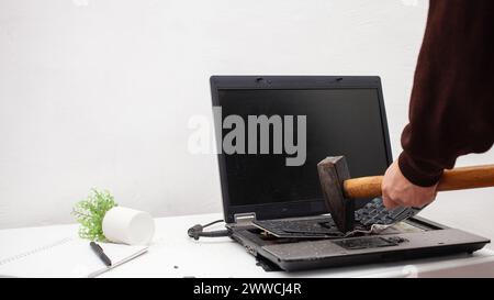 Ein Büroangestellter zerschlug einen Laptop, zerstörte einen Computer. Wut, Hass, Irritation. Fehler, Bremse, Störung, will nicht funktionieren. Schlechte Emotionen. De Stockfoto