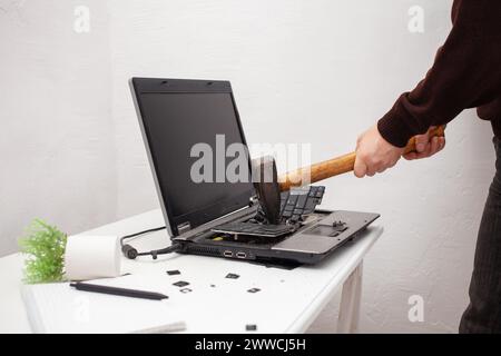 Ein Büroangestellter zerschlug einen Laptop, zerstörte einen Computer. Wut Hass, Irritation. Fehler, Bremse, Störung, will nicht funktionieren. Schlechte Emotionen. abt. Stockfoto