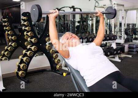 Ältere Frau mit grauem Haar spielt Sport im Fitnessstudio. Aktiver gesunder Lebensstil, Rentner, Seniorenkonzept. Rehabilitation nach Verletzungen, Stärkung im Stockfoto