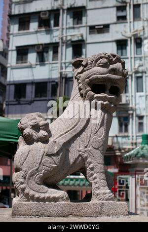 Die Skulptur eines chinesischen Schutzlöwen mit einer langen Zunge, die unten hängt, steht am man Mo Tempel in Hongkong. Stockfoto