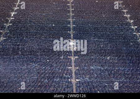 Nahaufnahme einer beschädigten zerbrochenen Solarzelle aus gehärtetem Glas. Steinbeulen in der Mitte mit Spinnennetzen. Stockfoto