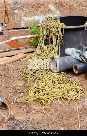 Gelbes Nylonseil in einem Haufen und Gusseisenrohre auf der Baustelle Stockfoto