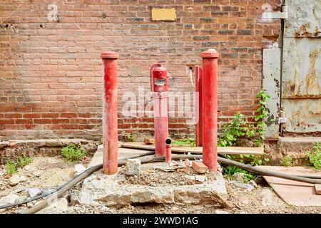 Rote Rohre und Pumpe, die aus Betonplatte steigen Stockfoto