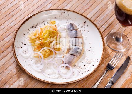 In Scheiben geschnittener Hering serviert mit Sauerkraut Stockfoto
