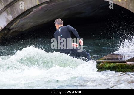 Ein Mann surft an einem Winternachmittag auf dem eisbach in München. Stockfoto