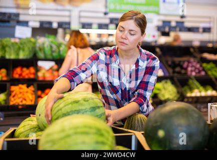 Frau wählt Wassermelone im Supermarkt Stockfoto