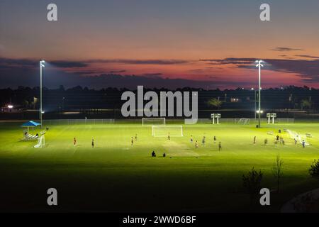 Sportlerinnen und Sportler trainieren im beleuchteten Fußballstadion im öffentlichen Sportpark in North Port, Florida Stockfoto