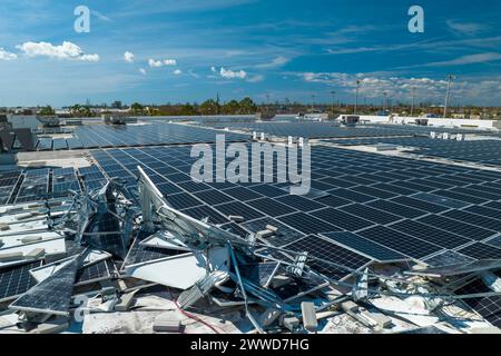 Draufsicht der durch den Hurrikan Ian zerstörten Photovoltaik-Solarpaneele, die auf dem Dach des Industriebaues zur Erzeugung von ökologischem Strom montiert sind Stockfoto