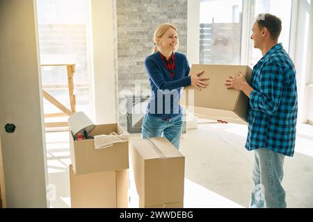 Glückliches Paar, das Kisten arrangiert, nachdem er in ein neues Haus gezogen ist Stockfoto