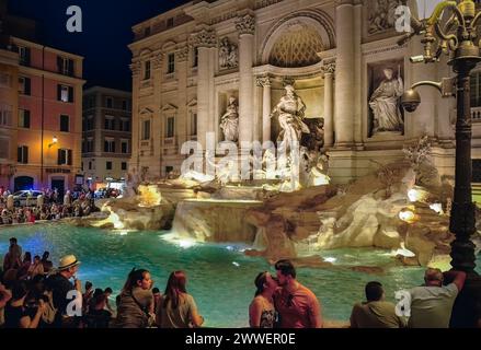 Blick auf den Trevi-Brunnen in Rom, Italien, bei Nacht; Mann und Frau im Vordergrund küssen Stockfoto