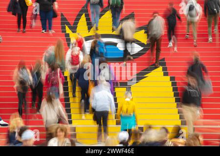 Besucher laufen auf einer Treppe mit dem Logo zur Buchmesse Leipzig am 22.03.2024 in der Glashalle der Leipziger Messe. Mehr als 2000 Ausstellerinnen und Aussteller aus 40 Laendern nehmen Teil. Auf dem Messegelaende sind parallel die Manga-Comic-Con seit 10 Jahren und die Antiquariatsmesse seit 30 Jahren dabei. Nach der Frankfurter Buchmesse ist die Leipziger Buchmesse derzeit die zweitgroesste Deutschlands. Besucher gehen eine Treppe mit dem Logo hinauf zur Leipziger Buchmesse, die am 22. März 2024 in der Glashalle der Leipziger Messe liest. Mehr als 2.000 Aussteller aus 40 Ländern Stockfoto