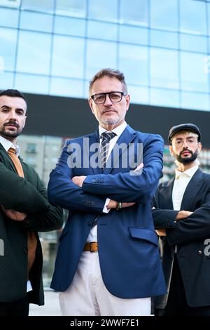 Eine Gruppe Männer in Anzügen, die ein Lächeln teilen, stehen vor einem Gebäude Stockfoto