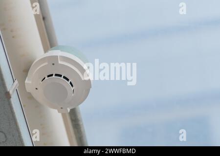Elektronischer Rauchmelder an der Decke eines geschlossenen Fußgängergehäuses mit verschwommenem Plexiglas in Südkorea Stockfoto