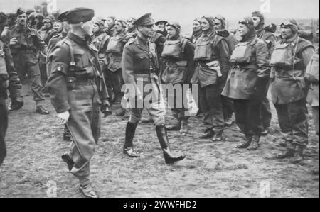 Ein Foto von etwa 1940 zeigt König Georg VI., der während des Zweiten Weltkriegs kanadische Soldaten inspiziert. Dieser Moment unterstreicht die Bemühungen des Königs, sich persönlich mit Truppen aus dem gesamten Commonwealth zu verbinden und sie zu unterstützen, und demonstriert damit seine Führung und sein Engagement für die alliierten Streitkräfte. Stockfoto