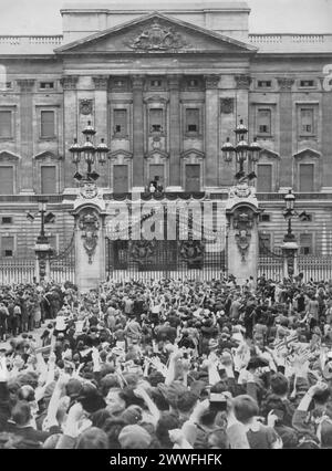 Ein Foto von 1945 zeigt Menschenmassen, die an den Toren des Buckingham Palace über den Sieg des Zweiten Weltkriegs feiern. Auf dem Balkon sind König George VI., Königin Elizabeth (die Königin Mutter) und Prinzessin Elizabeth II. Zu sehen, die diesen Moment des Triumphes mit der Nation teilen. Stockfoto