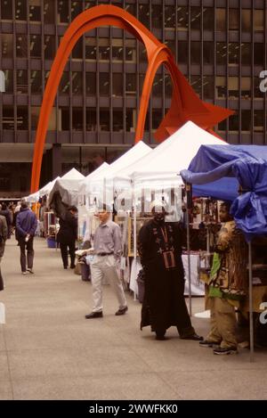 Chicago, Illinois, USA - Federal Center Plaza, afrikanisches Kunsthandwerk und Souvenirs zum Verkauf. Alexander Calders Flamingo-Skulptur im Hintergrund Stockfoto