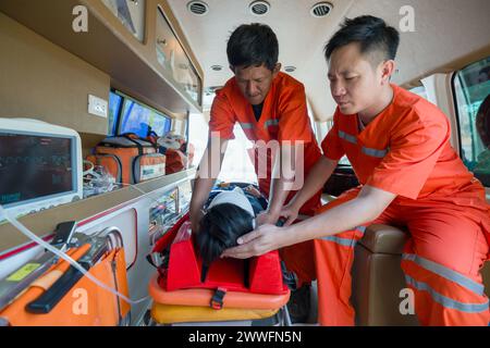 Zwei Sanitäter in orangefarbenen Uniformen helfen einem Patienten in einem Krankenwagen. Stockfoto