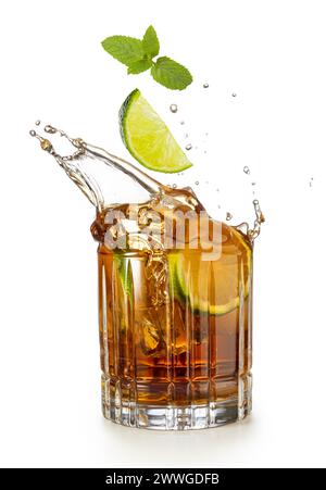 Kalkkkeil und Minze fallen in ein spritzendes Glas Rum und Koks, isoliert auf weißem Hintergrund. Stockfoto