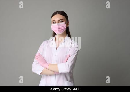 Kosmetologe in medizinischer Uniform auf grauem Hintergrund Stockfoto