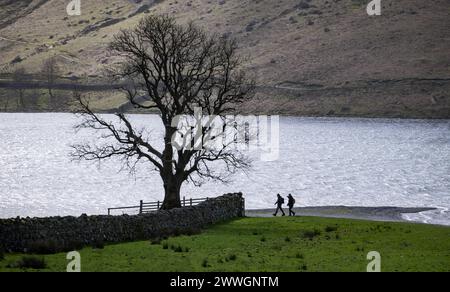 Spaziergänger am Ufer von Buttermere im englischen Lake District an einem Frühlingsmorgen in Cumbria, England. Stockfoto