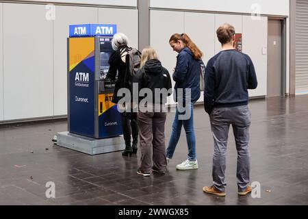 Leipzig, Deutschland. März 2024. Besucher der Leipziger Buchmesse stehen an einem Geldautomat in einer Ausstellungshalle an. Über 2000 Aussteller aus 40 Ländern präsentierten ihre neuen Produkte auf dem Frühjahrstreffen der Buchbranche. Quelle: Jan Woitas/dpa/Alamy Live News Stockfoto