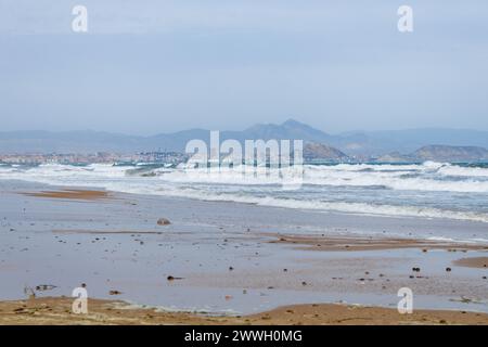 Starker windiger Tag über der Bucht von Alicante mit der Stadt im Hintergrund und starken Wellen vom Strand El Altet, Spanien Stockfoto