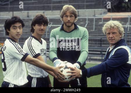 Karl-Heinz Feldkamp Re. mit Arminia-Spielern 07/83 stroe Karl-Heinz Feldkamp Re. mit Spielern am Rande eines Mannschaftsfototermins des DSC Arminia Bielefeld am 14. Juli 1983 auf der Alm in Bielefeld, v.li.: Kazuo Ozaki, Matthias Westerwinter und Wolfgang Kneib Deutschland deutsch deutscher Mann Männer Fans Fußball Sport Sportler Fußballspieler Fußballtrainer Bundesliga Liga Bielefelder Torwart Torhüter deutscher Fußballtrainer quer halb stehend sprechend lächelnd neutral Ball hält Seidensticker Sponsor Adidas *** Karl Heinz Feldkamp rechts mit Arminia-Spielern 07 83 stroe Karl Heinz Feld Stockfoto