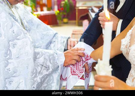 Traditionelle christliche Hochzeit. Der Priester fesselte seine Hände an das Brautpaar mit einem Hochzeitstuch auf der Kirche. Stockfoto