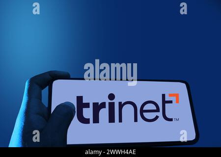 Boy's Hand öffnet die TriNet-Anwendung auf dem Bildschirm, wobei der Beschneidungspfad in blau verwischt ist Stockfoto