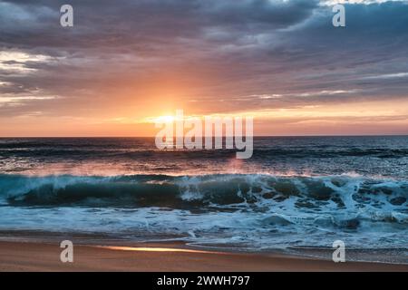 Wellen des altlantischen Ozeans brechen auf den Strand an der cote de Argent in Frankreich mit goldenem Sonnenuntergang im Hintergrund, Cap Ferret, Aquitaine, Fran Stockfoto