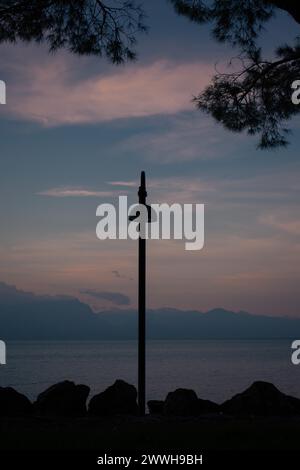 Silhouetten einer Straßenlaterne und Äste vor einem Abendhimmel, Berge und Gardasee im Hintergrund, Sirmione, Gardasee, Italien Stockfoto