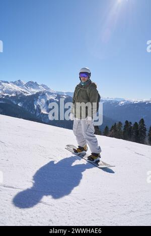 Ein Snowboarder blickt auf die Berge und ist bereit, die Pisten zu besteigen. Stockfoto