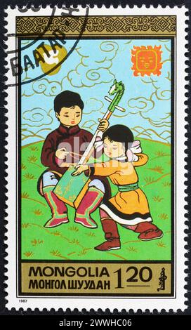 Von der Mongolei gedruckte, annullierte Briefmarke, die die Aktivitäten der Kinder zeigt, um 1987. Stockfoto