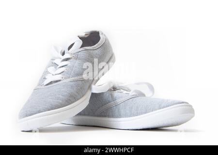 Turnschuhe sind grau isoliert auf weißem Hintergrund. Damen-Sneaker. Unisex-Schuhe. Beitrag über den Schaden von Schuhen mit Gummisohlen. Turnschuhe sind gr Stockfoto
