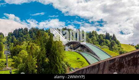 München, Deutschland - August 2021: Seitenansicht der Olympia-Schanze und Bergbahnblick der Alpen. Olympia München, Deutschland - A München, Deutschland - August 2021 Stockfoto