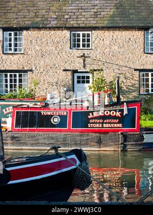 Altes, hell bemaltes historisches Boot, das vor einem Kanalhaus am Grand Union Canal bei Stoke Bruerne, England, Großbritannien, Northa vor Anker liegt Stockfoto