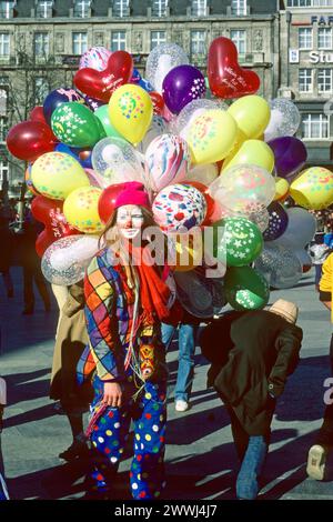 Junge Frau im Clown-Kostüm, die Ballons beim Karnevalsumzug 1982 in Köln, Nordrhein-Westfalen verkauft Stockfoto