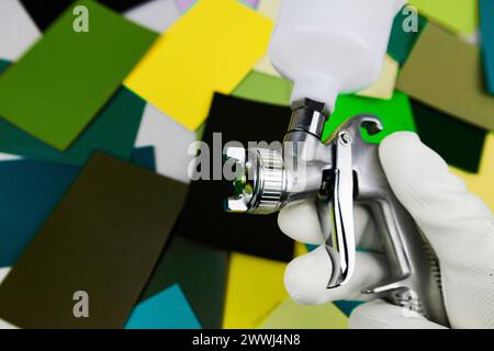 Lackierpistole bei der Arbeit am Arbeitsplatz in der Werkstatt, Auswahl der Werkzeuge, Farbmuster. Stockfoto