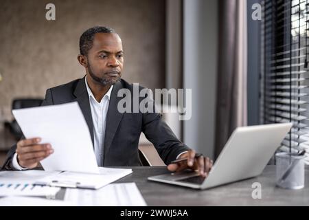 Seriöser, selbstbewusster Geschäftsmann Finanzier am Arbeitsplatz, der Dokumente, Berichte und Verträge überprüft. Leitender Mann im Business-Anzug, der an Papierkram arbeitet, Buchhalter bei Konten. Stockfoto
