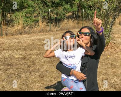 Mutter und Tochter, die während einer Sonnenfinsternis in einem Landpark die Sonne betrachten, Familienaktivitäten im Freien. Stockfoto