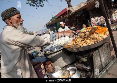 Ein muslimischer Mann bereitet eine Portion chicken Biryani in der Altstadt von Delhi, Indien Stockfoto