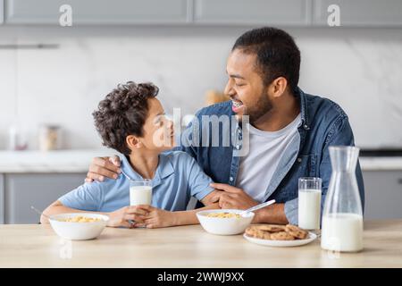 Glücklicher afroamerikanischer Vater und Sohn frühstücken zusammen Stockfoto