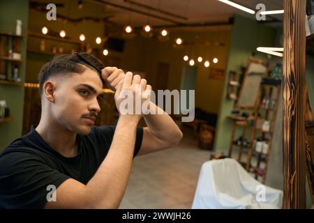 Coiffeur kämmte sich im Friseurladen, während er auf Gäste wartete Stockfoto