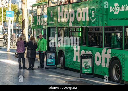 Hop-on-Hop-off-Busfahrer, der Touristen zu einer Stadtrundfahrt mit dem Bus einlädt. O’Connell Street, Dublin. Irland. Stockfoto