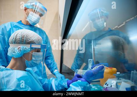 Laborpersonal arbeitet mit Biomaterialien unter Einhaltung der Sicherheitsvorkehrungen Stockfoto