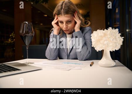 Einsame Frau in einem Restaurantsaal mit Kopfschmerzen Stockfoto