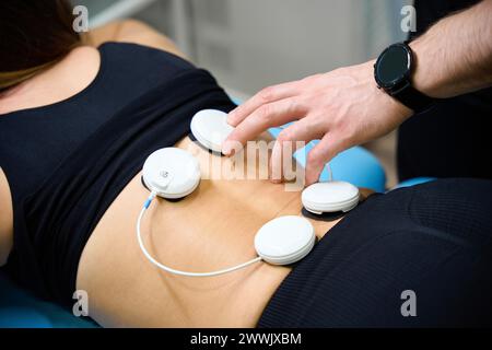 Der Arzt verwendet einen elektrischen Muskelstimulator für das Wellness-Verfahren im Rehabilitationszentrum Stockfoto