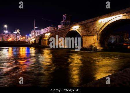 Beleuchtete Gebäude und Lichter in der Nähe eines Flusses bei Nacht in Skopje im Norden Mazedoniens Stockfoto